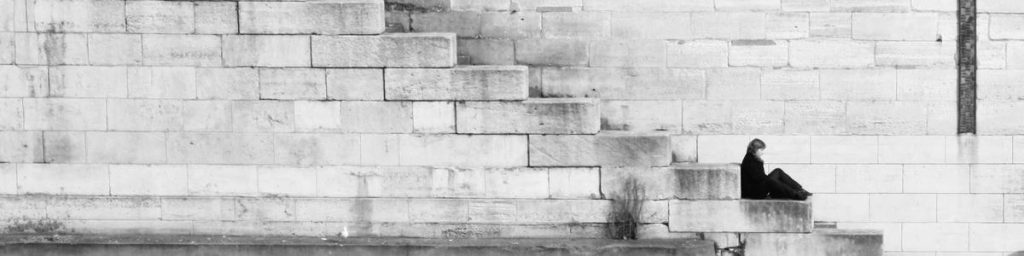 Persona sentada en un muro blanco